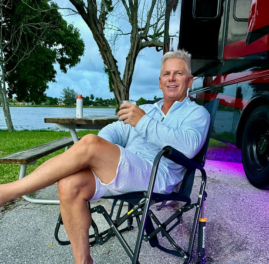 Man sitting in rocking camping chair at campground.