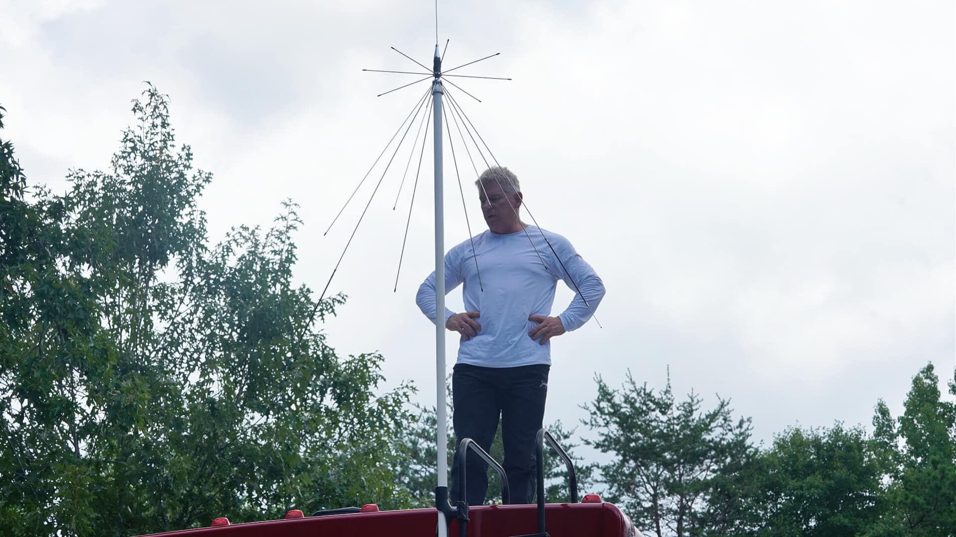 Wideband scanner antenna on a pole on top of an RV with man stsanding next to it