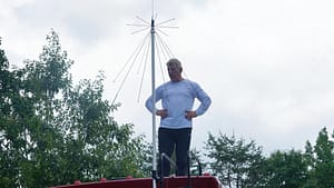 Wideband scanner antenna on a pole on top of an RV with man stsanding next to it