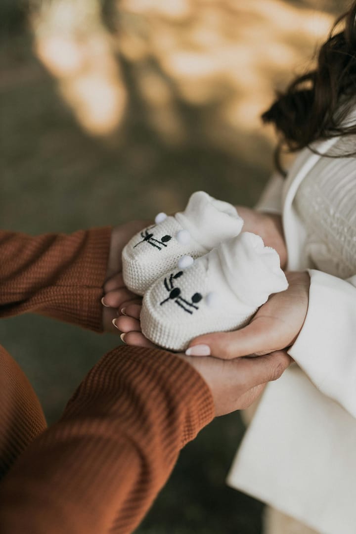 A couple holding adorable knit baby booties symbolizing upcoming parenthood.
